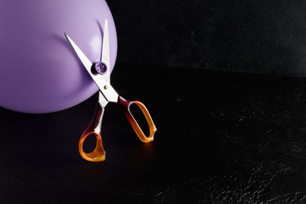 Scissors threatening to cut a balloon