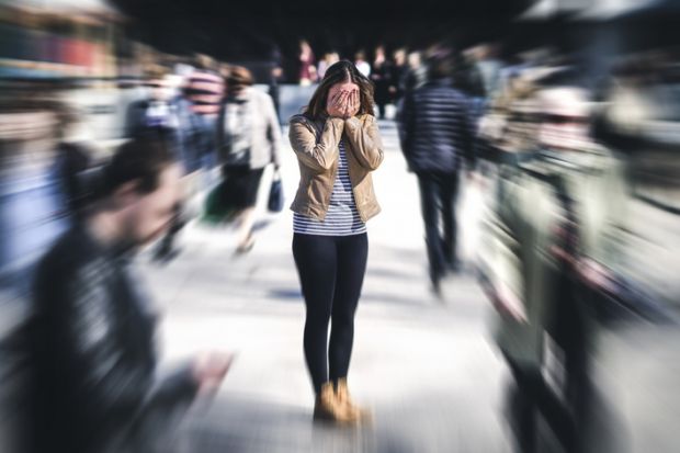 A woman in a crowd covers her face in shame