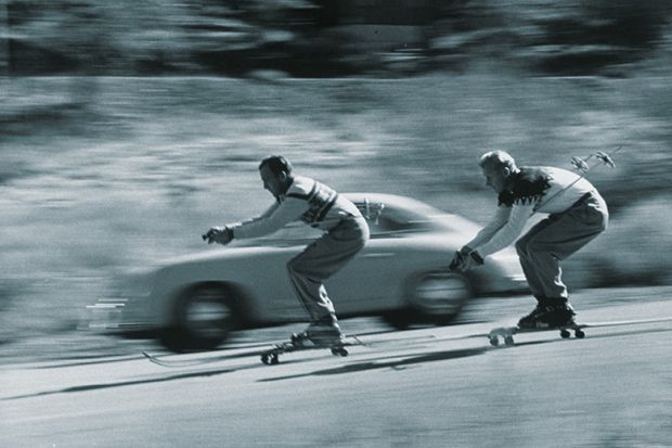 Skiers racing car down hill