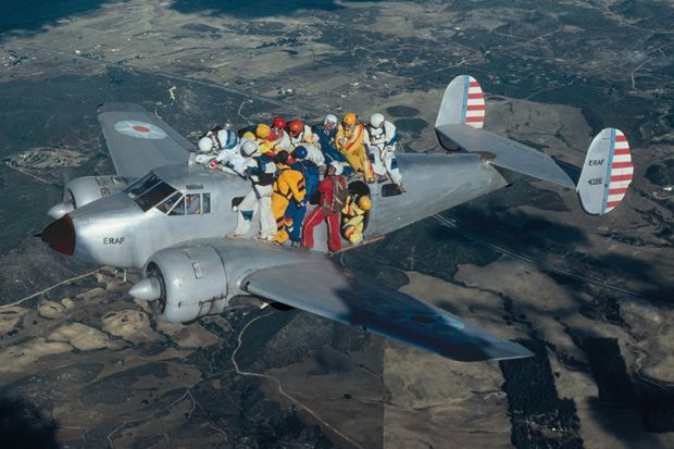 Skydivers holding on to aeroplane in flight