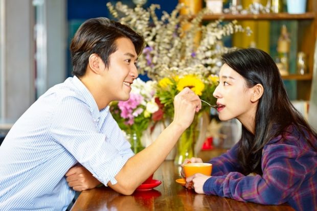 A man spoon-feeding a woman