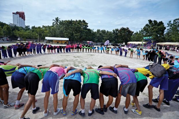 Students in linked circle on beach