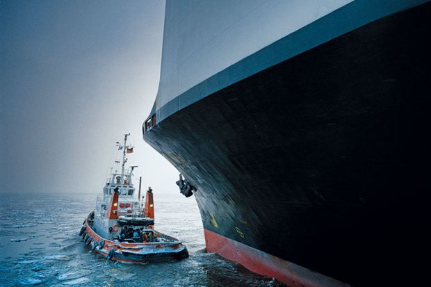 tugboat with giant cargo ship