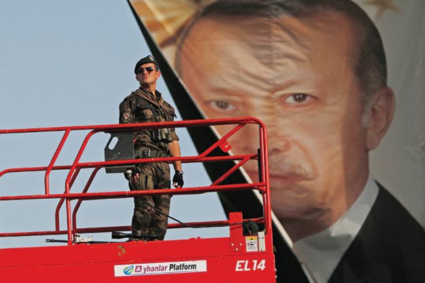 Turkish police officer standing in front of poster of President Recep Tayyip Erdoğan