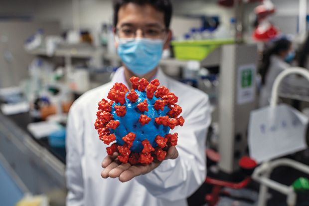 Scientist with model of coronavirus