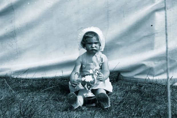 Unhappy child holding a winners cup to illustrate Teaching awards are  for losers, not winners