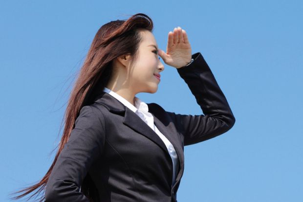 Young woman shielding eyes and looking into distance