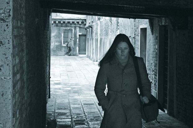 Young woman walking through archway, Venice, Italy