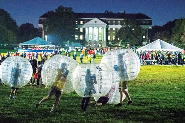 People in plastic bubbles play on a field