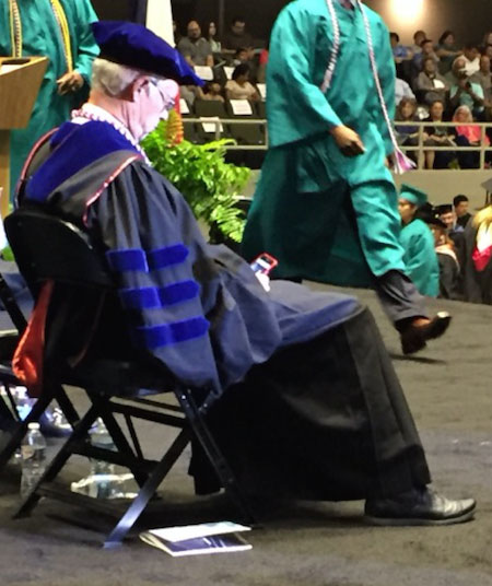 University chancellor using smartphone on stage