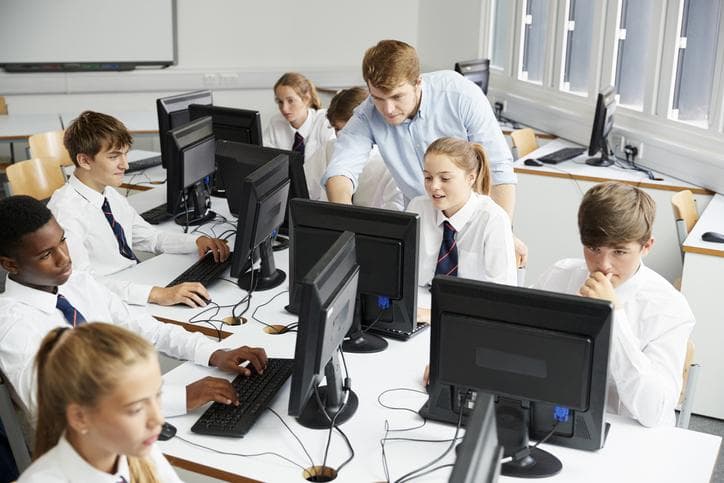 Teacher helping students on computer 