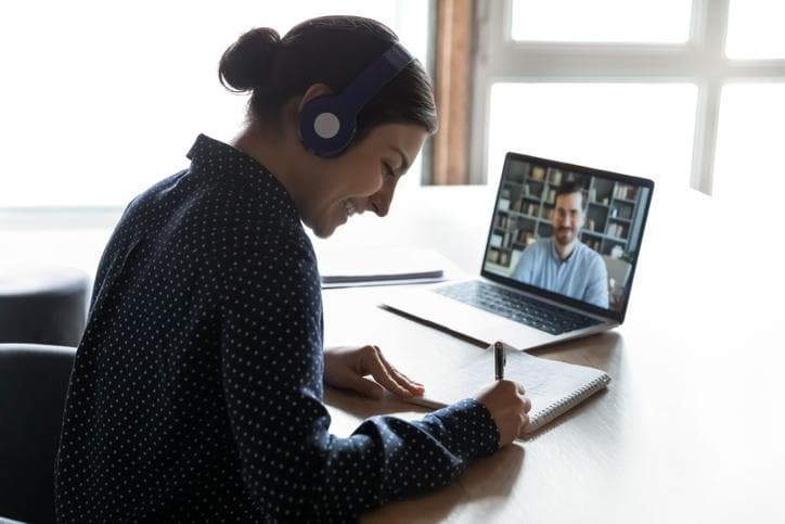 Student making notes from video on laptop