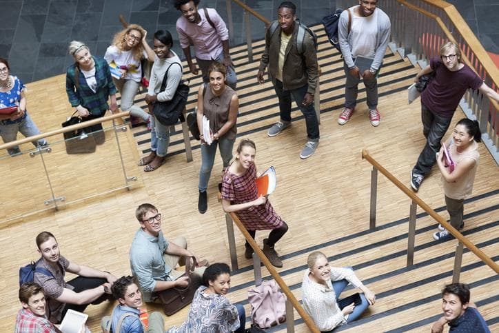 university students looking up from the staircase and smiling