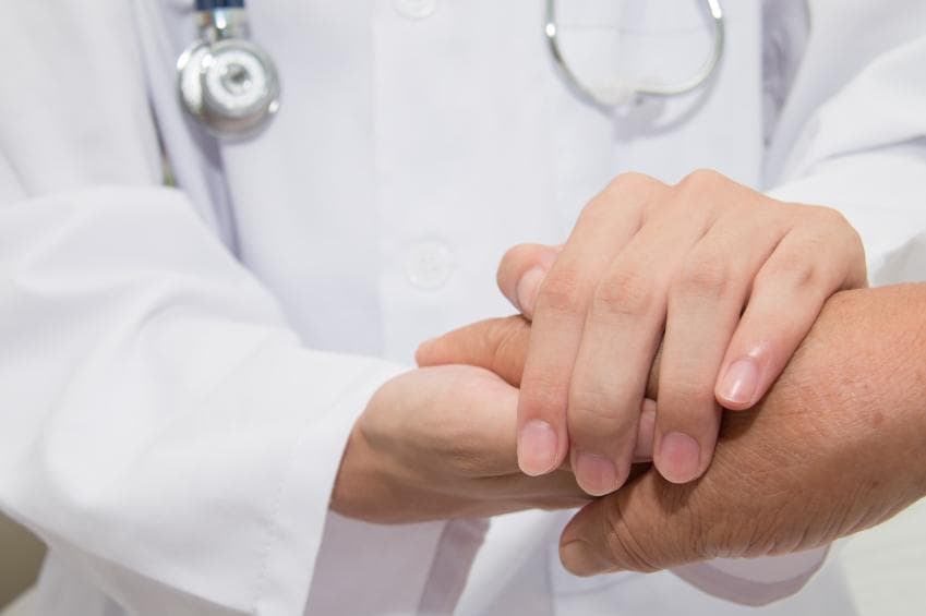 Doctor holding hands with patient